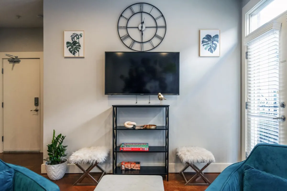 A cozy and modern seating area with a wall-mounted television, decorative shelves, plants, and a stylish arrangement of seats. This space is perfect for relaxing, watching TV, or socializing with guests.